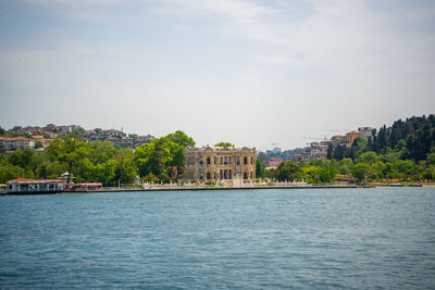 Buildings by river against sky