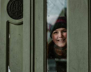 Portrait of smiling young woman against door