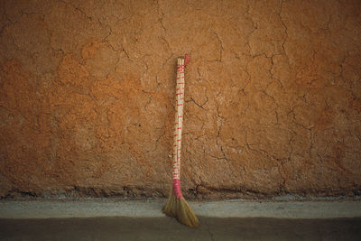 Broom leaning on cracked brown wall