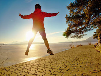 Sports girl practices aerobics and runs through the morning park by the lake