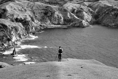 Rear view of photographing rocky sea shore