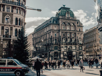 People walking on street in city against sky