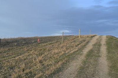 Road amidst field against sky