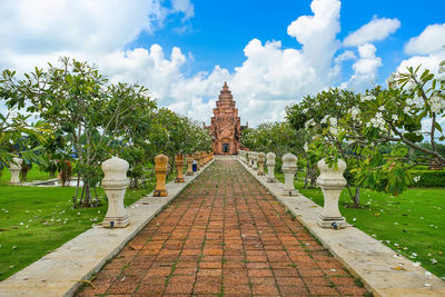 Footpath leading towards temple building against sky