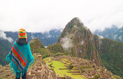 Female visitor impressed by spectacular ancient inca ruins of machu picchu citadel, cusco, peru