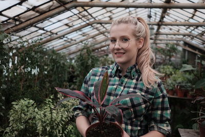 Portrait of a smiling young woman in greenhouse