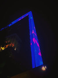 Low angle view of illuminated lighting equipment in building at night