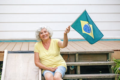Proud citizen celebrating independence day of brazil. happy old woman with brazilian flag outdoor