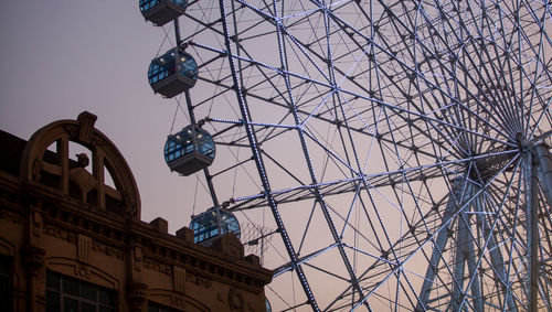 Low angle view of ferris wheel against building