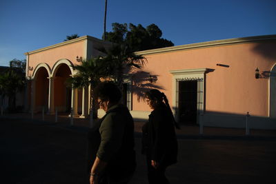 Silhouette people standing on street against building