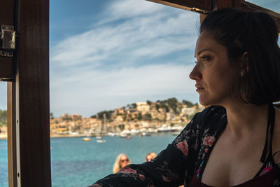 Woman looking at sea through window