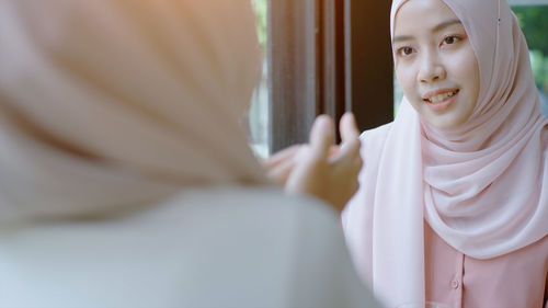 Beautiful young woman in hijab looking at mirror