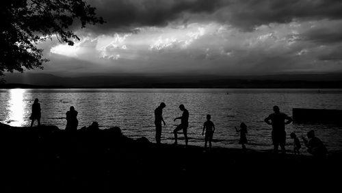 Silhouette people on beach against sky