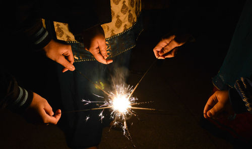 Rear view of man holding sparkler at night