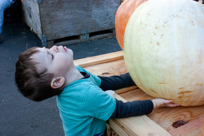 Cute boy holding pumpkin on wood