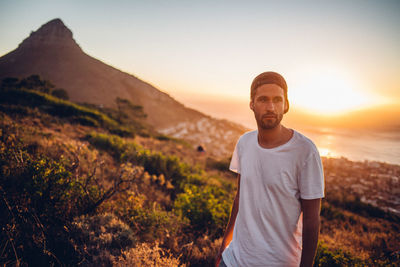 Young man standing on land against sky during sunset