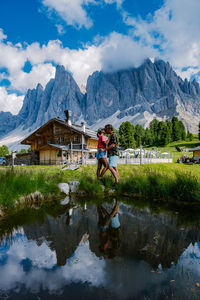 People on lake by mountains against sky