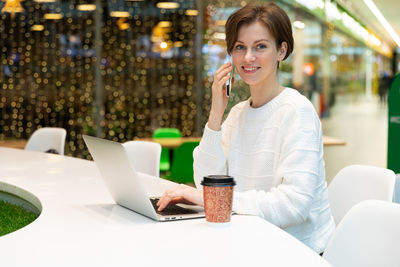 Portrait of smiling woman talking on phone in cafe