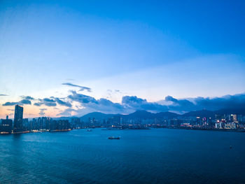 Scenic view of sea by city against blue sky