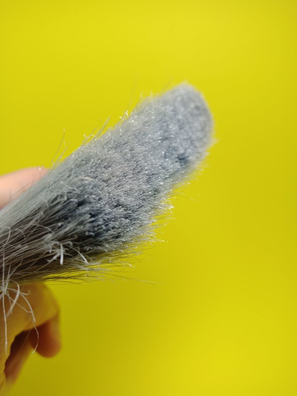 CLOSE-UP OF HAND HOLDING YELLOW LEAF AGAINST GRAY BACKGROUND