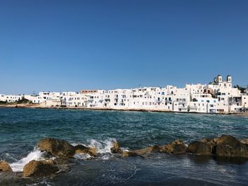 Scenic view of sea and buildings against clear blue sky