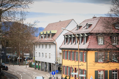 Residential buildings by street against sky