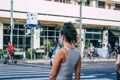 Rear view of people walking on road in city