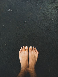 Low section of man standing on wet road