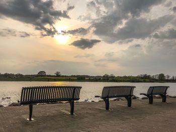 Empty bench on table against sea during sunset