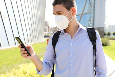 Man using mobile phone against buildings