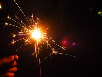 Close-up of hand holding illuminated sparkler at night