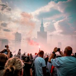 Rear view of people photographing against sky