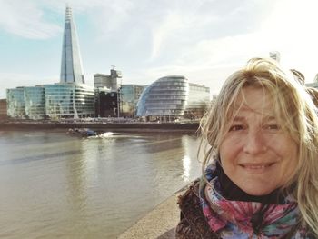 Portrait of woman with gla building in background in city