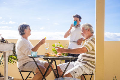 Senior couple having drinks with grandson at balcony