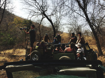 Group of people sitting by bare tree