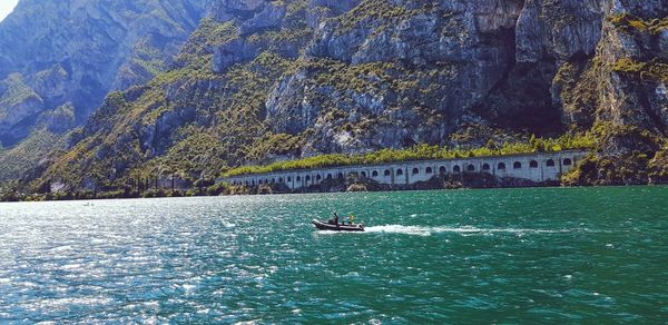 Boat sailing on sea against mountain