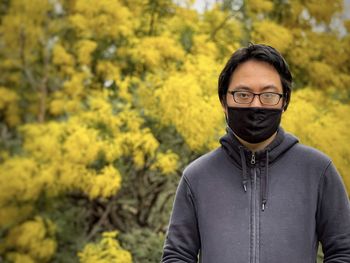 Portrait of young man standing against yellow plants