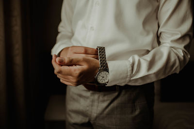 Midsection of man getting dressed while standing at home