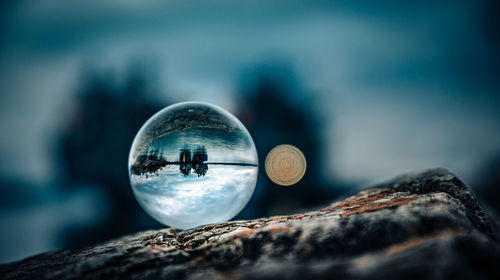 Close-up of crystal ball on rock against sky