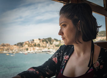 Portrait of woman looking away against sky