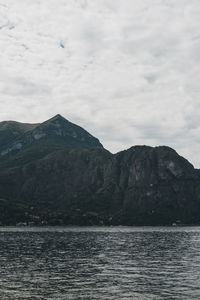Scenic view of sea by mountain against sky