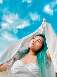 Low angle view of woman sitting against sky