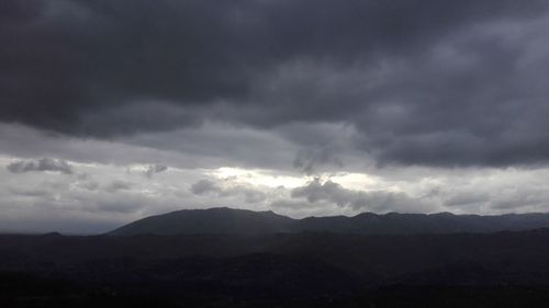 Scenic view of silhouette mountains against storm clouds
