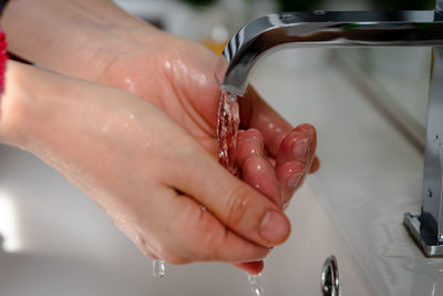 Cropped image of hand holding faucet in water