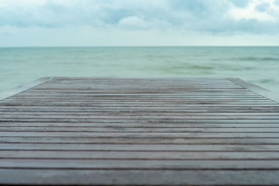 Surface level of wooden pier over sea against sky