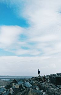 Man standing on rock against sky