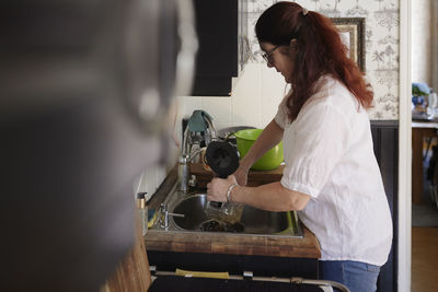 Mature woman washing dishes in kitchen