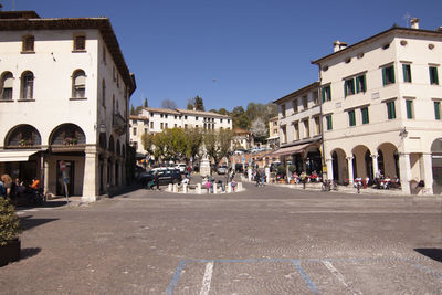 People on street amidst buildings in city against sky