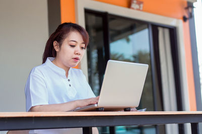 Young woman using phone while sitting on table