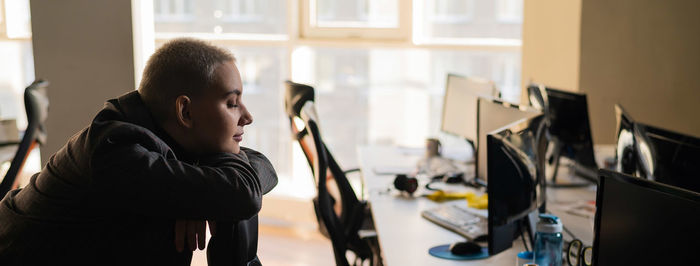 Side view of woman sitting at office